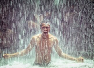 Homem tomando banho de cachoeira, feliz e imerso na natureza, com água caindo ao seu redor, representando a prática de Shinrin-yoku ou banho de floresta.