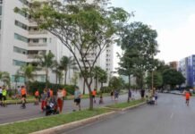 Pessoas praticando atividades recreativas em rua arborizada no Guará, com prédios residenciais ao fundo.