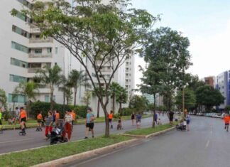 Pessoas praticando atividades recreativas em rua arborizada no Guará, com prédios residenciais ao fundo.