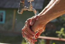 Homem lavando as mãos com água limpa, simbolizando acesso ao saneamento básico