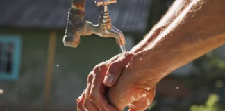 Homem lavando as mãos com água limpa, simbolizando acesso ao saneamento básico