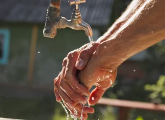 Homem lavando as mãos com água limpa, simbolizando acesso ao saneamento básico