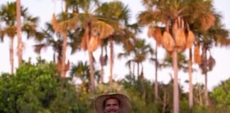 Foto mostra uma pessoa que vive do cerrado, atras dela há uma vegetação nativa do cerrado