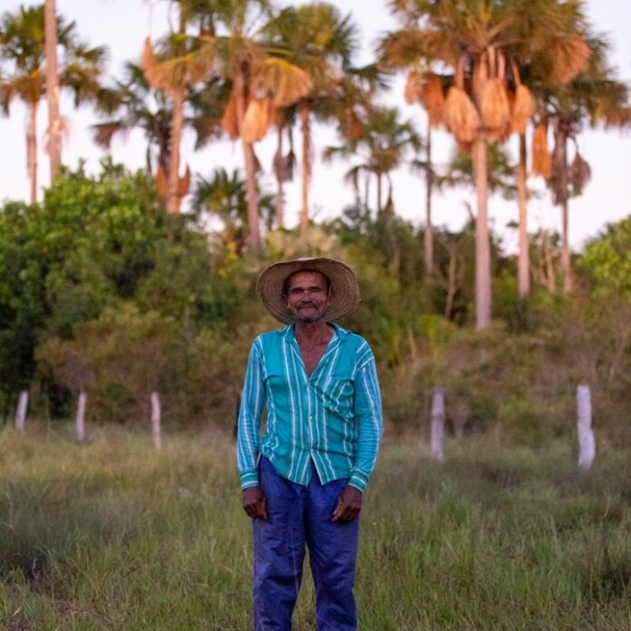 Foto mostra uma pessoa que vive do cerrado, atras dela há uma vegetação nativa do cerrado