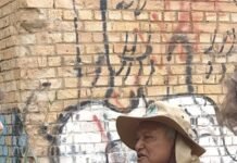 Grupo de escoteiros e moradores reunidos em frente a mural histórico na Candangolândia durante a Trilha Pirá-Brasília.