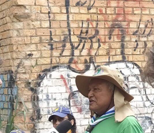 Grupo de escoteiros e moradores reunidos em frente a mural histórico na Candangolândia durante a Trilha Pirá-Brasília.